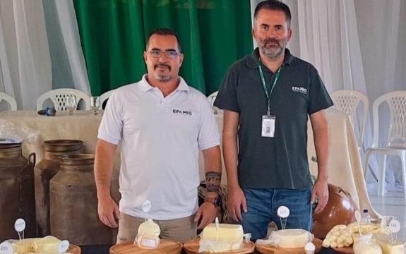 Dois homens em frente à mesa com queijos