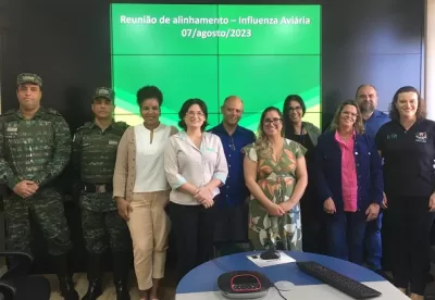 dez pessoas em pé e atrás delas uma tela escrito reunião de alinhamento - Influenza Aviaria 7 agosto 2023