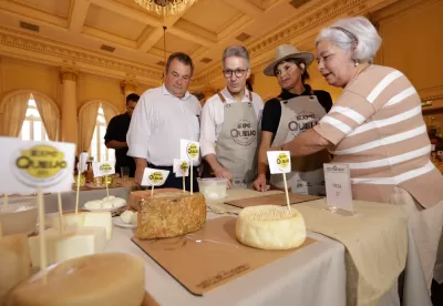 O secretário de Agricultura, Thales Fernandes, o governador Romeu Zema, a organizadora da Expoqueijo, Maricell, e a diretora-presidente da Epamig, Nilda Soares, olham para uma mesa com diversos queijos do concurso internacional.