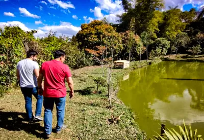 Produtor Marcos e seu filho Vítor andam em volta de um lago na propriedade