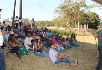 pessoas sentadas no chão escutando palestrante