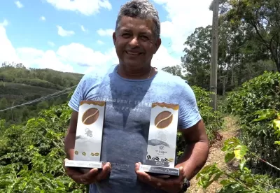 Agricultor vencedor do concurso ostenta dois prêmios, um em cada mão