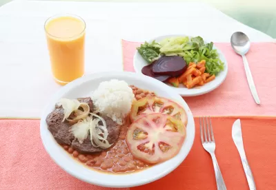 dois pratos expostos com comida em cima da mesa com um copo de suco ao lado esquerdo