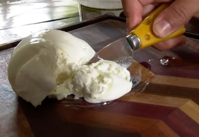 queijo em cima de uma tabua sendo cortado por uma faca