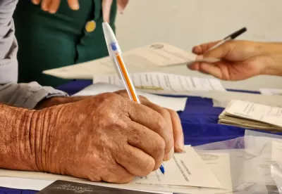 Foto em plano detalhe de produtor assinando o título de sua terra