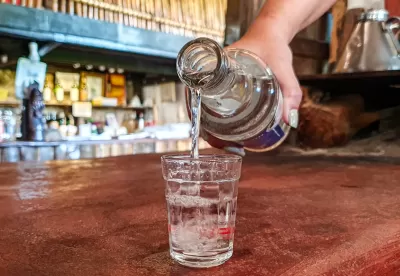 Imagem de uma mão colocando cachaça no copo