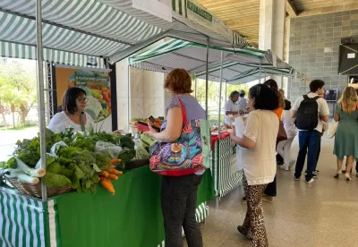 barracas com feirantes ao lado esquerdo da imagem com pessoas circulando