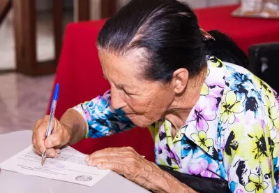 Senhora assinando documento de regularização fundiária rural