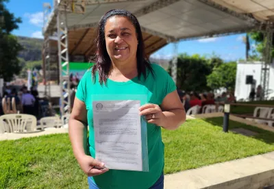 Foto mostra agricultora Salete da Conceição Cruz Costa, segurando o título de seu imóvel