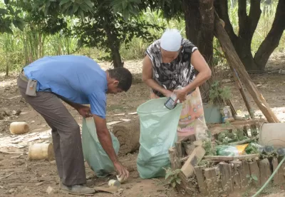Foto mostra casal de produtores rurais recolhendo o lixo e colocando dentro de sacos plásticos