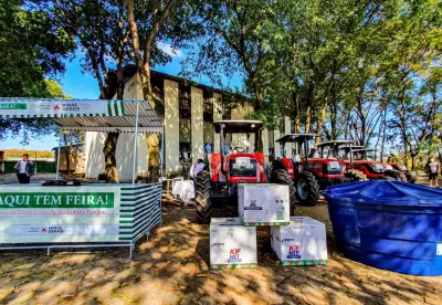 Foto com um kit feira livre e uma retroescavadeira vermelha.