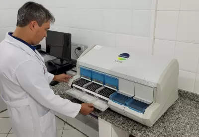 pesquisador da epamig de pé olhando para o imunoanalisador Vidas 30 sobre um balcão de granito ao lado de um computador no laboratório do instituto de laticínios candido tostes
