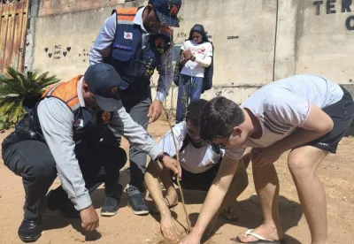 Alunos e autoridades plantando árvores no terreno da escola durante a comemoração do Dia Mundial do Meio Ambiente