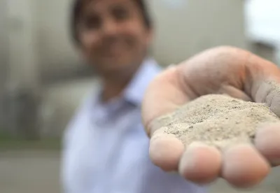 Foto mostra mão mostrando o agrosilício em primeiro plano