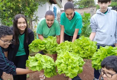 Alunos mostram o resultado da colheita da horta escolar