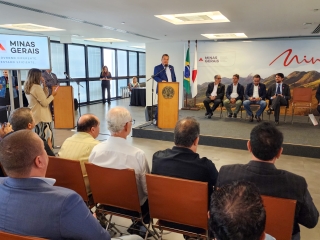secretário de agricultura thales fernandes discursa com público no primeiro plano e autoridades sentadas do lado direito, tv do lado esquerdo com a logomarca do governo de minas e a inscrição governo diferente estado eficiente