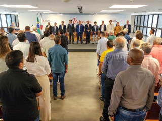 publico de pé enquanto escutam o hino nacional e dispositivo de autoridades ao fundo também de pé durante solenidade de doação de fertilizantes pela harsco
