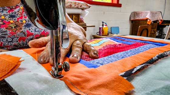 Mão de costureira fazendo uma colcha de retalhos na máquina