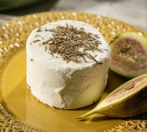 Queijo de leite de cabra em um prato amarelo, ornamentado com especiarias e figos.