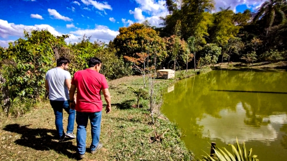 Produtor Marcos e seu filho Vítor andam em volta de um lago na propriedade
