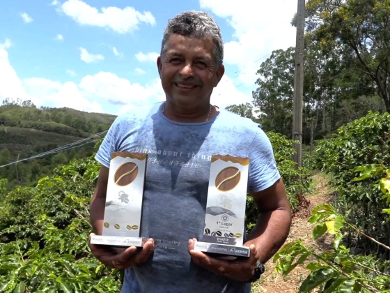 Agricultor vencedor do concurso ostenta dois prêmios, um em cada mão