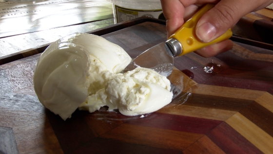 queijo em cima de uma tabua sendo cortado por uma faca