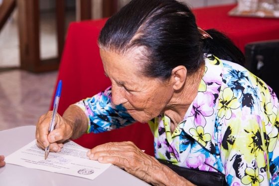 Senhora assinando documento de regularização fundiária rural