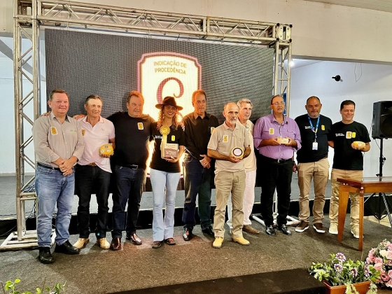 Foto mostra Secretário Thales Fernandes e os produtores segurando o Queijo Minas Artesanal do Serro com o Selo de Indicação Geográfica na embalagem