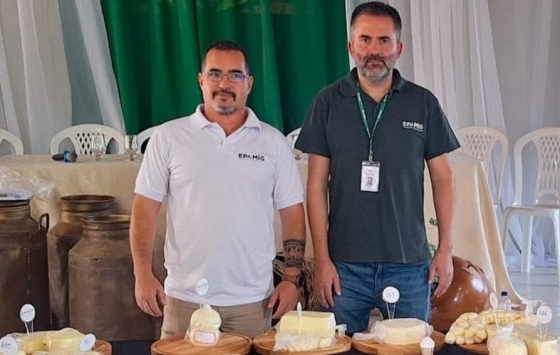 Dois homens em frente à mesa com queijos