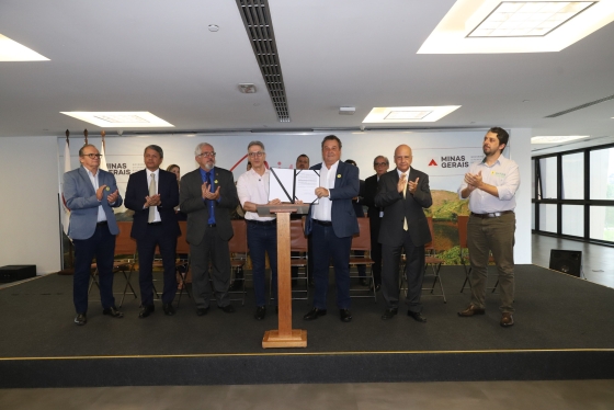 Foto mostra governador Romeu Zema e secretário de Agricultura Thales Fernandes segurando acordo assinado com municípios para o início do programa de regularização fundiária