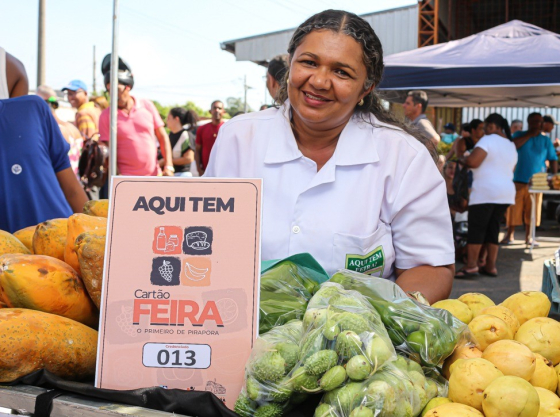 mulher segura cartão de feira atrás de sua mesa