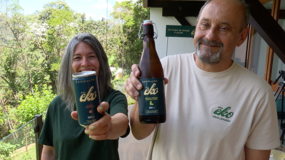 Foto mostra casal segurando as embalagens de kombucha