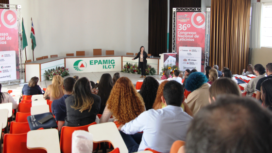 Foto de palestra feita em um auditório com várias pessoas participando