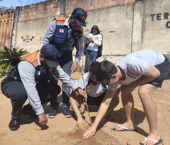 Alunos e autoridades plantando árvores no terreno da escola durante a comemoração do Dia Mundial do Meio Ambiente