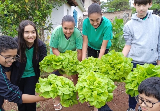 Alunos mostram o resultado da colheita da horta escolar