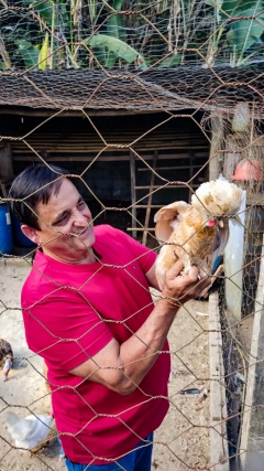 O produtor Marcos segurando uma galinha dentro do galinheiro